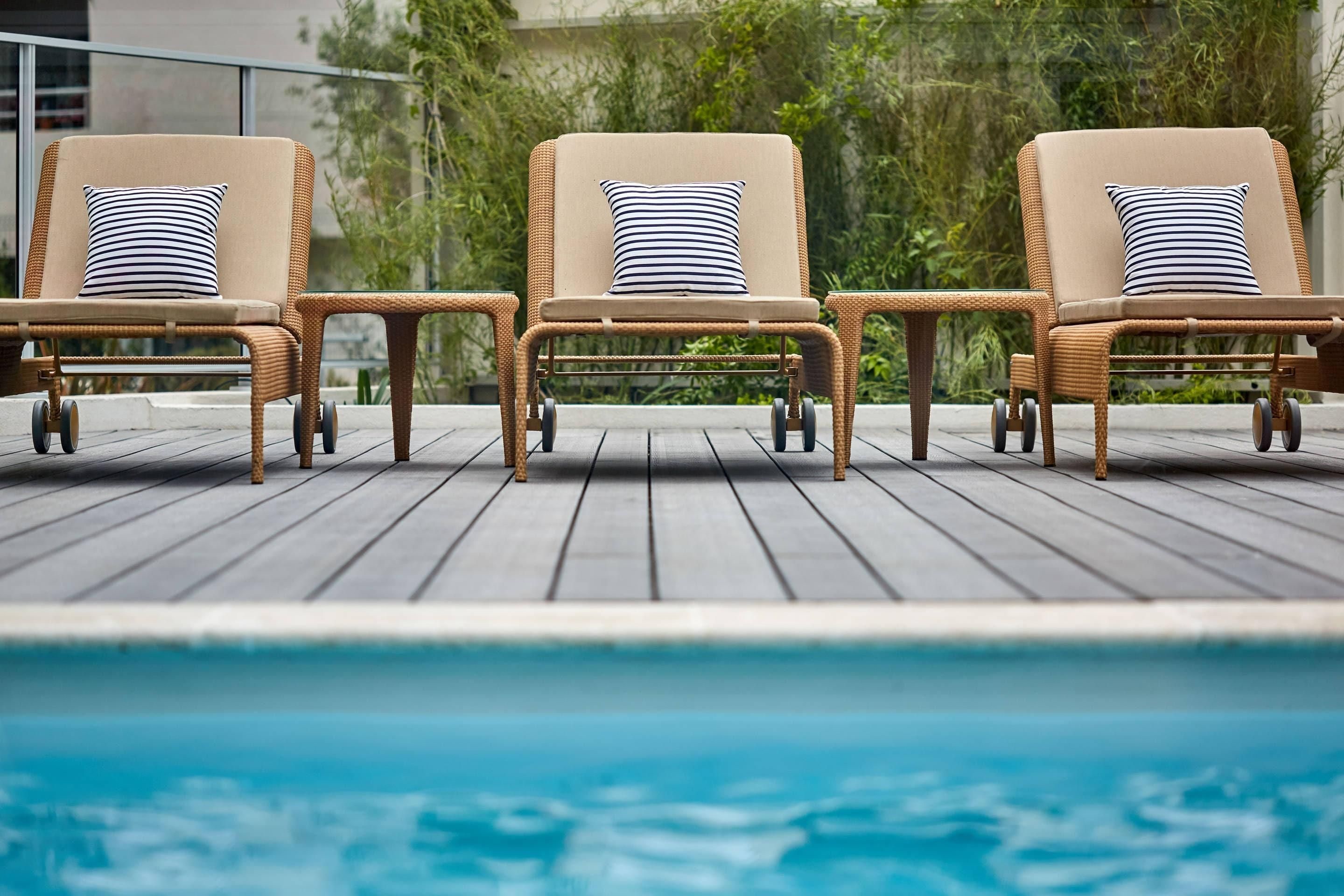 Drei Korbsessel mit gestreiften Kissen am Pool.