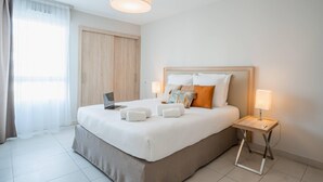 Une chambre d’hôtel avec un lit, des lampes de chevet, un ordinateur portable et une fenêtre avec des rideaux.