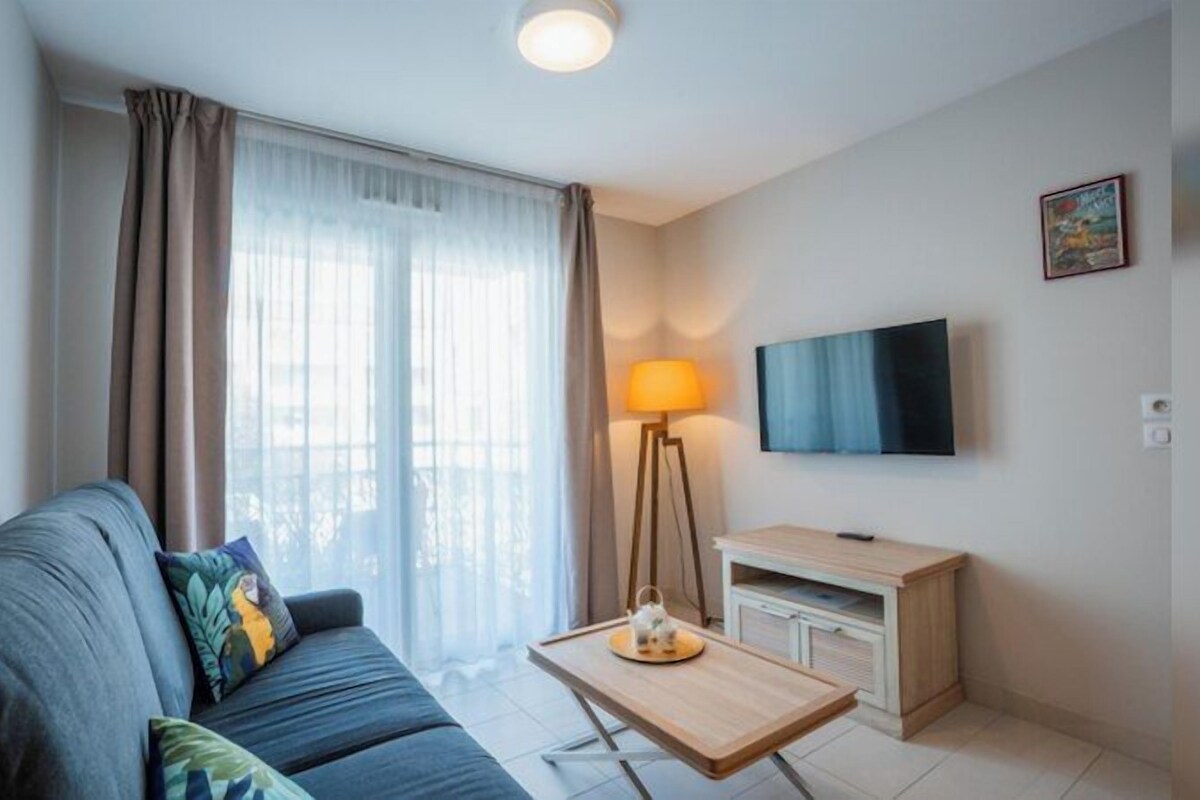 Una sala de estar con sofá, mesa de centro, lámpara, televisor y un mueble bajo.