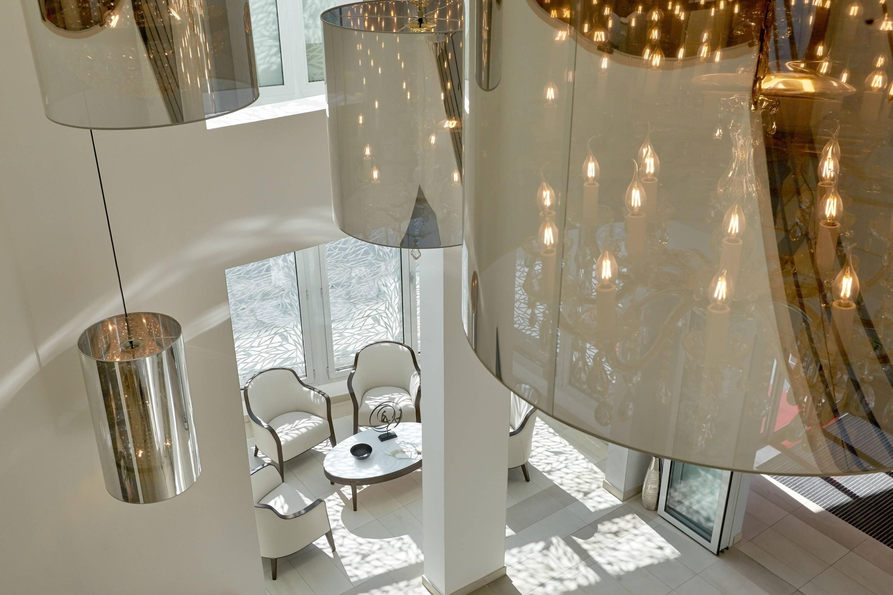Un intérieur moderne avec un plafond haut, des surfaces réfléchissantes et un espace salon doté d’une table ronde.