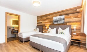 Ett hotellrum med två sängar, träpanel på väggarna, ett badrum med spegel och handfat samt en tavla ovanför sängarna.