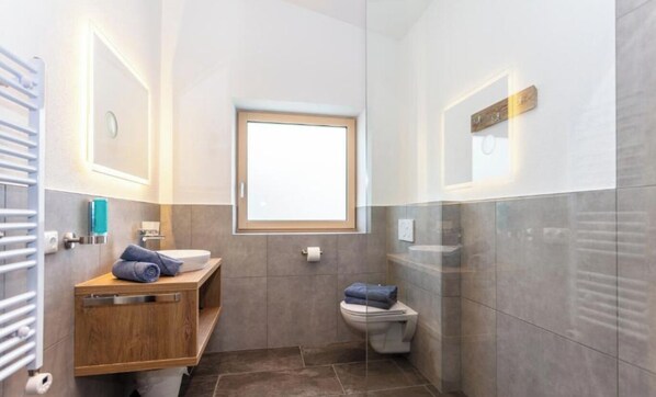 Une salle de bain moderne avec un meuble-lavabo en bois, des toilettes et une fenêtre.