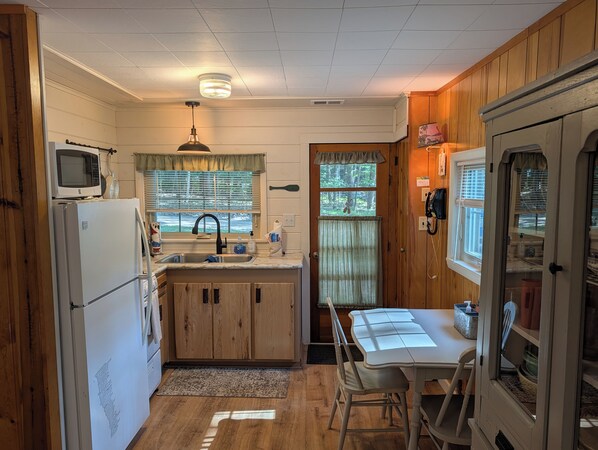Una cocina funcional con refrigerador, microondas, lavamanos y armarios de madera.