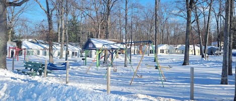Un parc enneigé avec des balançoires et une aire de jeux.