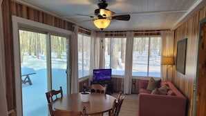 Una habitación acogedora con techo de madera, una mesa de comedor con sillas, un televisor y un sofá.