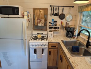Una cucina con fornello, forno a microonde e lavello.