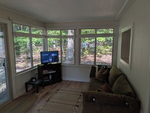 SUNROOM:  The sunroom has a sofa along with a streaming television. - The Higgins Lake Hideaway - Super Cute and Great Location Only 3 Blocks from Higgins Lake! (Roscommon)