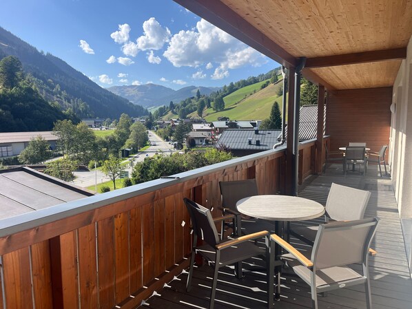 A balcony with wooden railings, a round table, and two chairs.