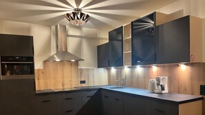 A modern kitchen with dark cabinets, a wooden countertop, a built-in oven, and a coffee maker.