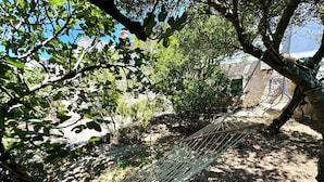 A hammock in a natural setting with trees and a stone structure in the background. - Holiday house Adria (Crikvenica)