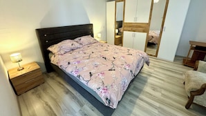 A bedroom with a bed, wooden nightstands, a dresser, a mirror, and a chandelier. - Holiday house Adria (Crikvenica)