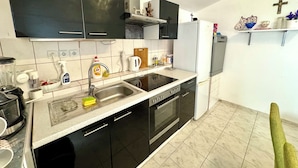 A modern kitchen with black cabinets, a stainless steel sink, and a built-in oven. - Holiday house Adria (Crikvenica)