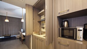 A modern kitchen with wooden cabinets, a built-in microwave, and a coffee maker. - Bloomfields STU with Balcony Leonardo (Abu Dhabi)