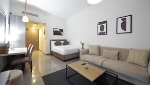 A modern hotel room with a bed, a sofa, a dining table, and a coffee table. - Bloomfields STU with Balcony Leonardo (Abu Dhabi)