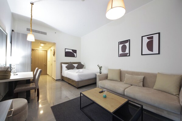 A modern hotel room with a bed, a sofa, a dining table, and a coffee table.