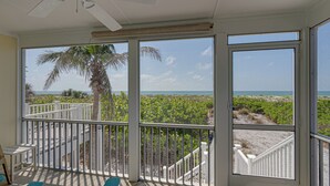Een balkon met uitzicht op het strand en palmbomen.