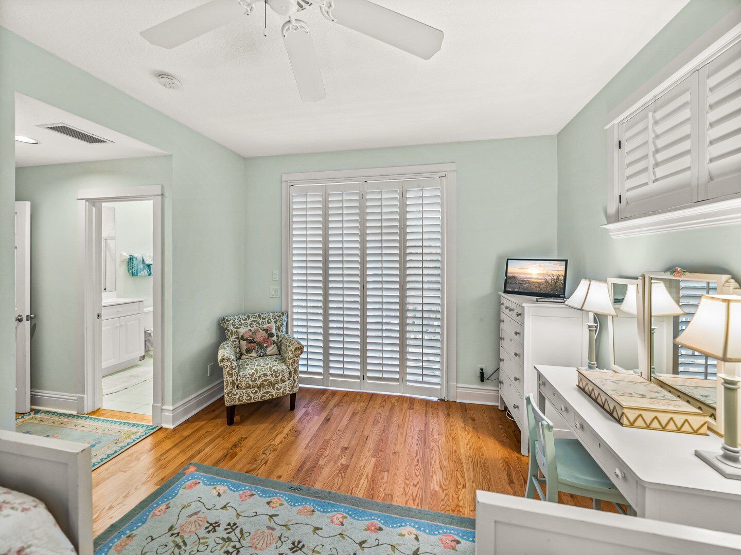 A bedroom with a ceiling fan, a bed, a chair, a dresser, and a TV.