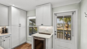 A kitchen with white cabinets, a built-in oven, and a window with a view of palm trees. - Bayfront Boca Grande North 43 - Top Floor - 2/2 Great Water Views! (Placida)