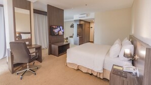 A hotel room with a bed, a desk, a chair, a TV, and a bedside table with a lamp. - Labersa Hotel & Convention Centre Toba (Balige)
