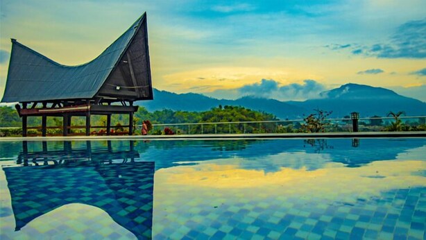 A swimming pool with a checkered pattern, a pavilion with a curved roof, and a mountainous landscape in the background. - Labersa Hotel & Convention Centre Toba (Balige)