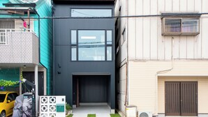 A modern two-story house with a garage, a covered car, and a small garden area. - Private House Hibiki (Nara)