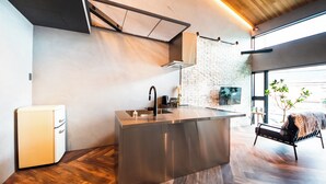 A modern kitchen with a built-in island, a small refrigerator, and a seating area with a bench. - Private House Hibiki (Nara)
