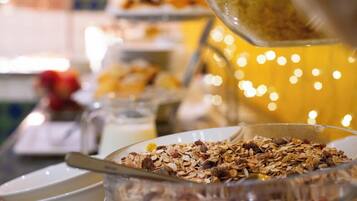 A breakfast buffet with various food items and a glass bowl filled with granola.