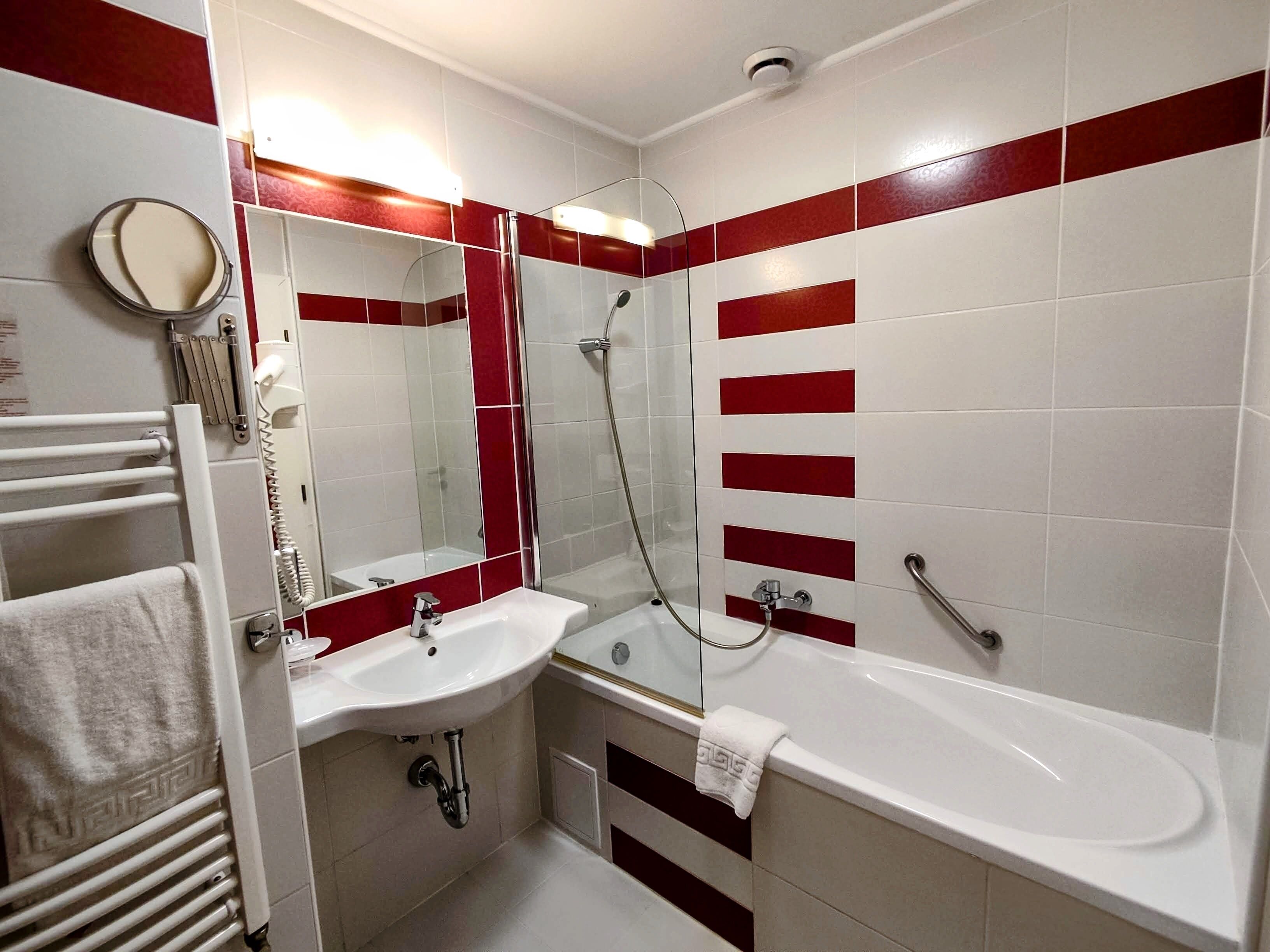 A modern bathroom with a white sink, a large bathtub, and a glass-enclosed shower.