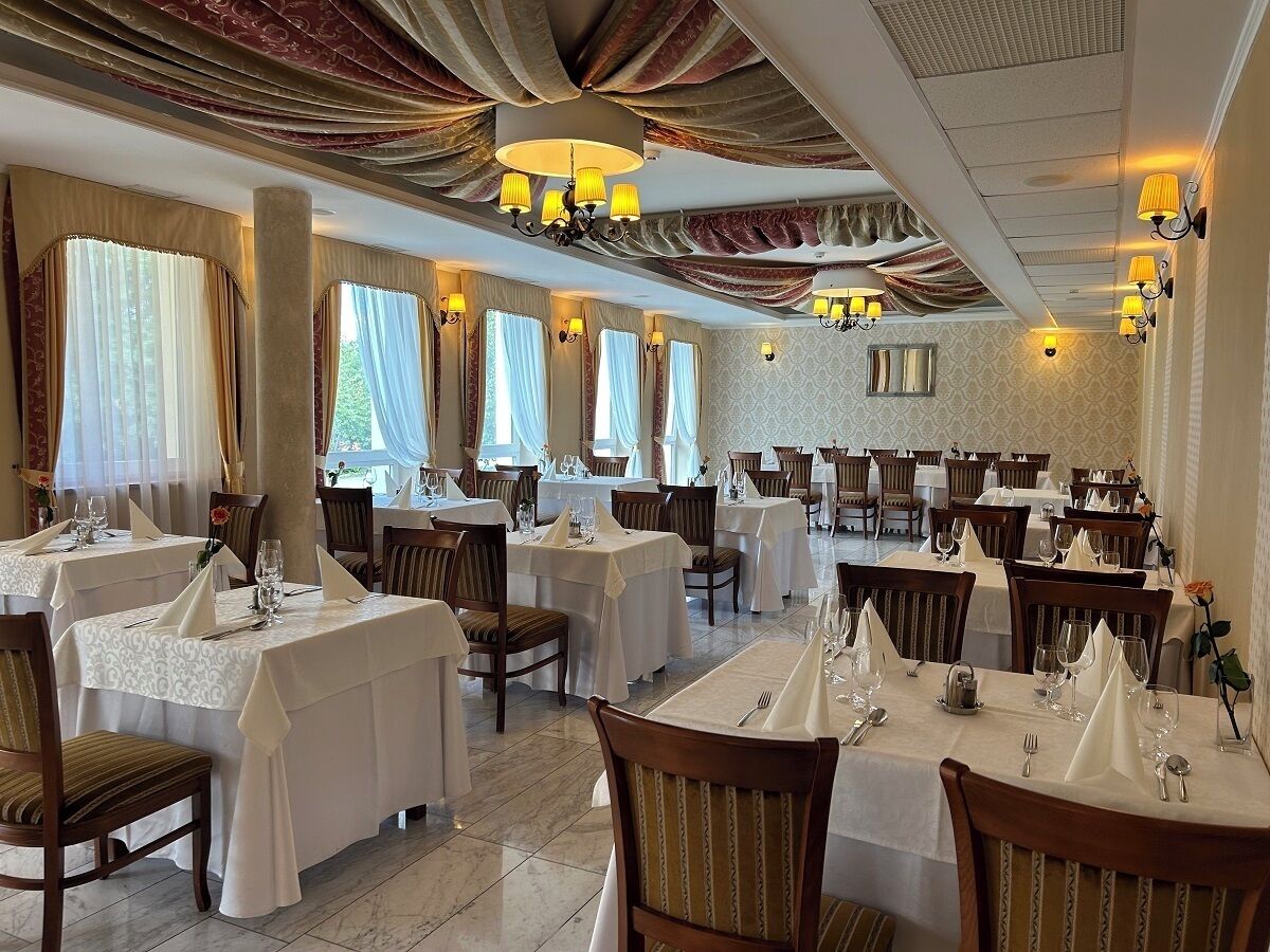 Un restaurante con varias mesas dispuestas para comer, con candelabros y cortinas.
