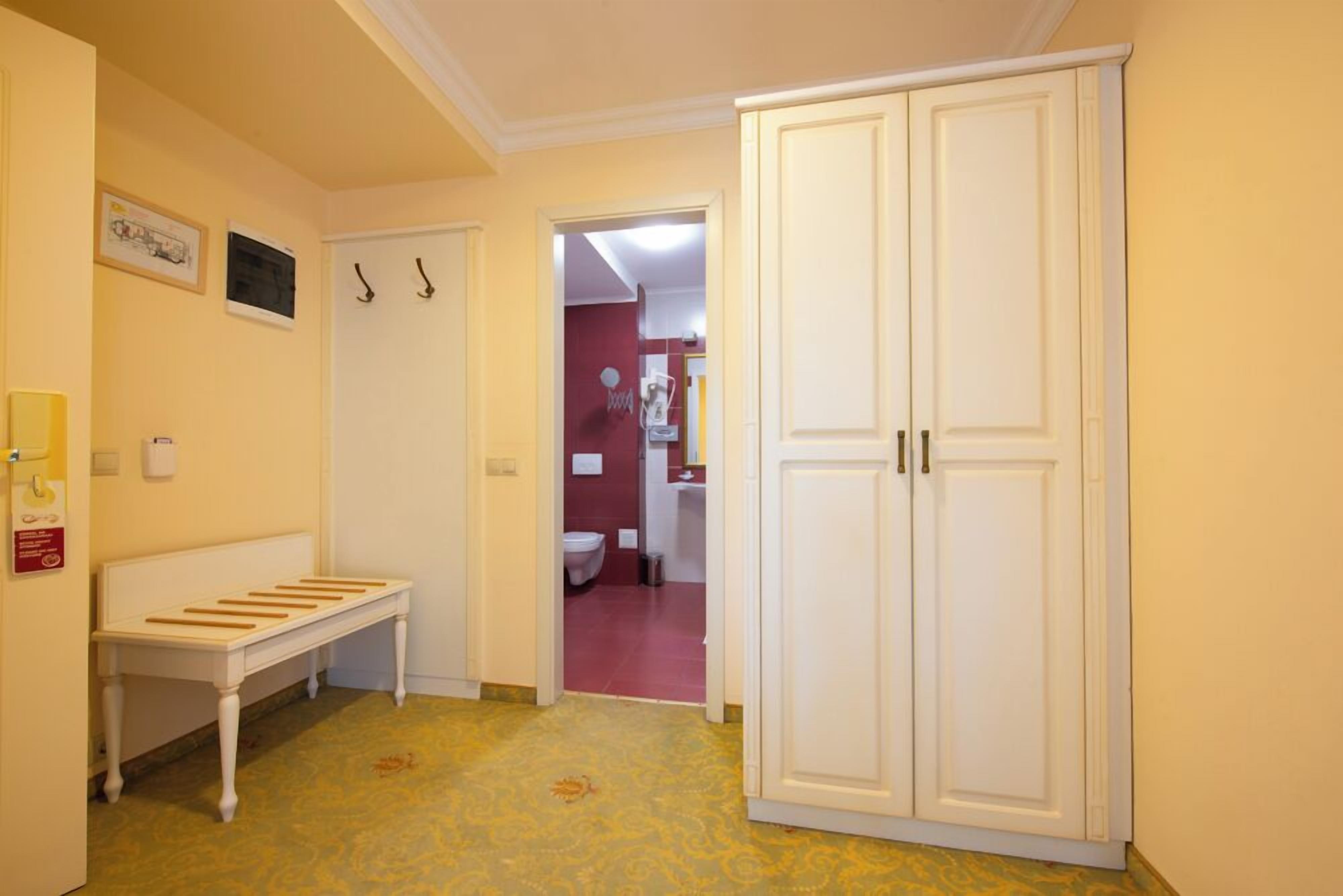 A hallway with a bench, a wardrobe, and a door leading to a bathroom.