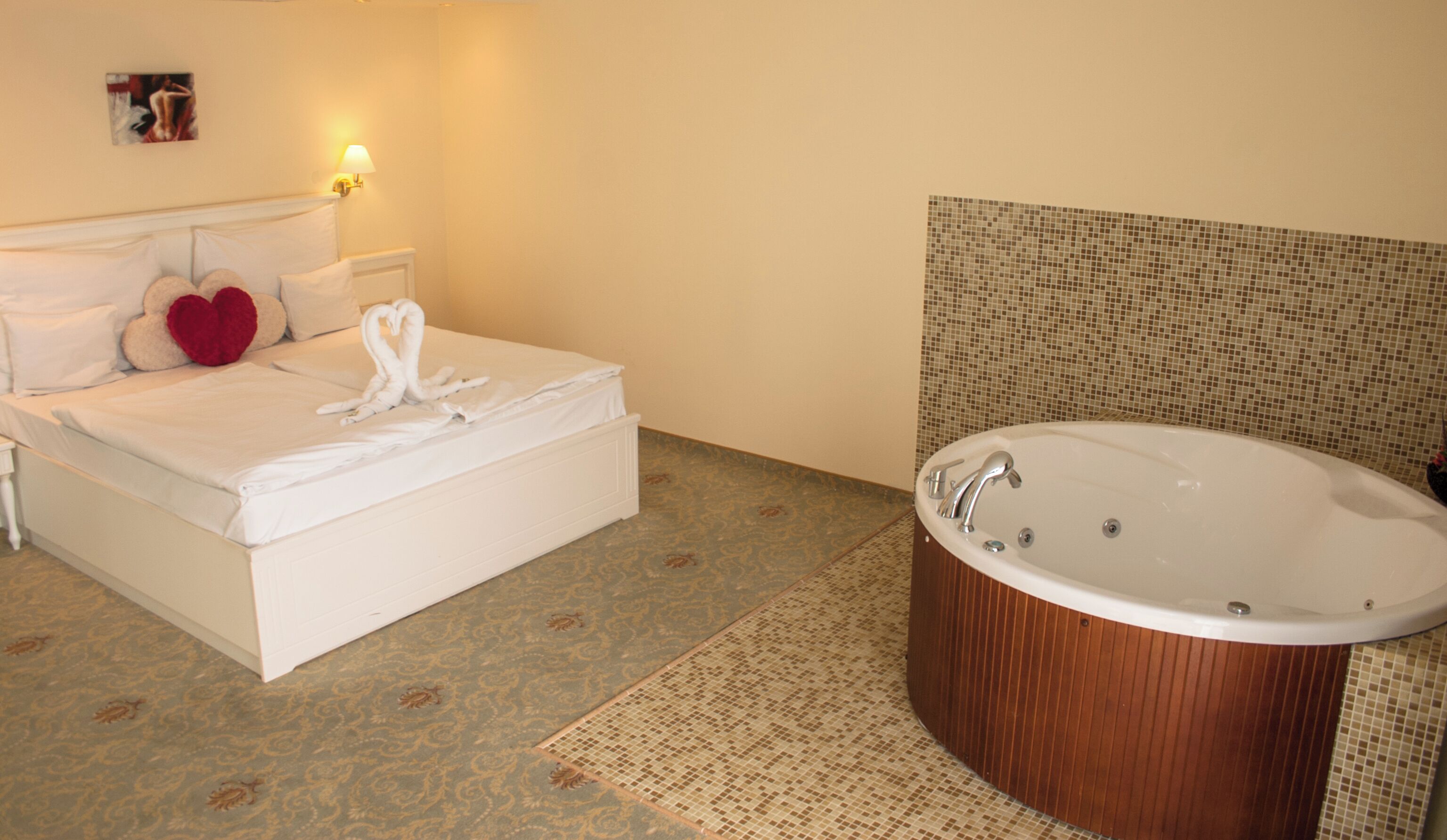 Habitació d'hotel amb llit, banyera gran i terra amb dibuixos.