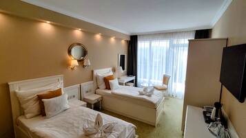 Habitación de hotel con dos camas, un escritorio, una silla, un televisor y una ventana con cortinas.
