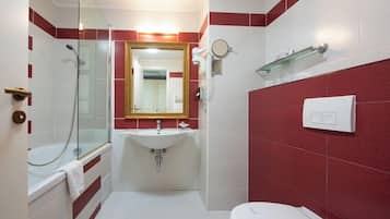 A bathroom with a glass-enclosed shower, a white sink, a mirror, and a toilet.