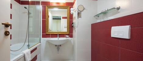 Un baño con ducha envuelta en vidrio, un lavamanos blanco, un espejo y un inodoro.