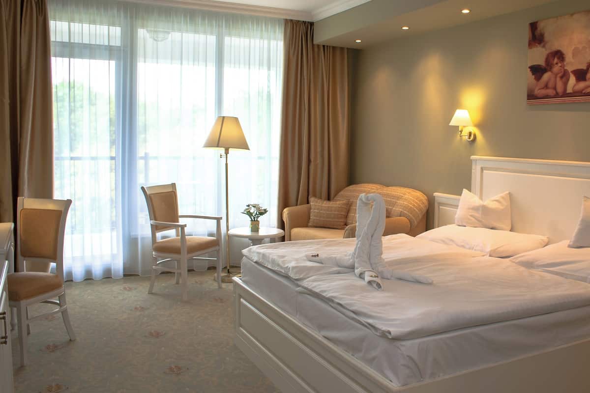Quarto de hotel com uma cama grande, uma cadeira, uma mesa e um abajur.
