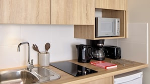 A modern kitchen with a stainless steel sink, a microwave, a coffee maker, and a toaster. - Quality Aparthotel Reims - Saint-Thomas (Reims)