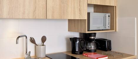 A modern kitchen with a stainless steel sink, a microwave, a coffee maker, and a toaster.