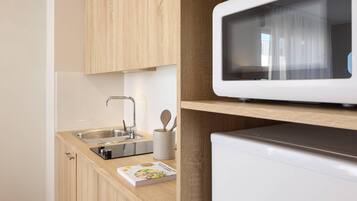 A modern kitchen with wooden cabinets, a stainless steel sink, a microwave, and a small appliance on the countertop.