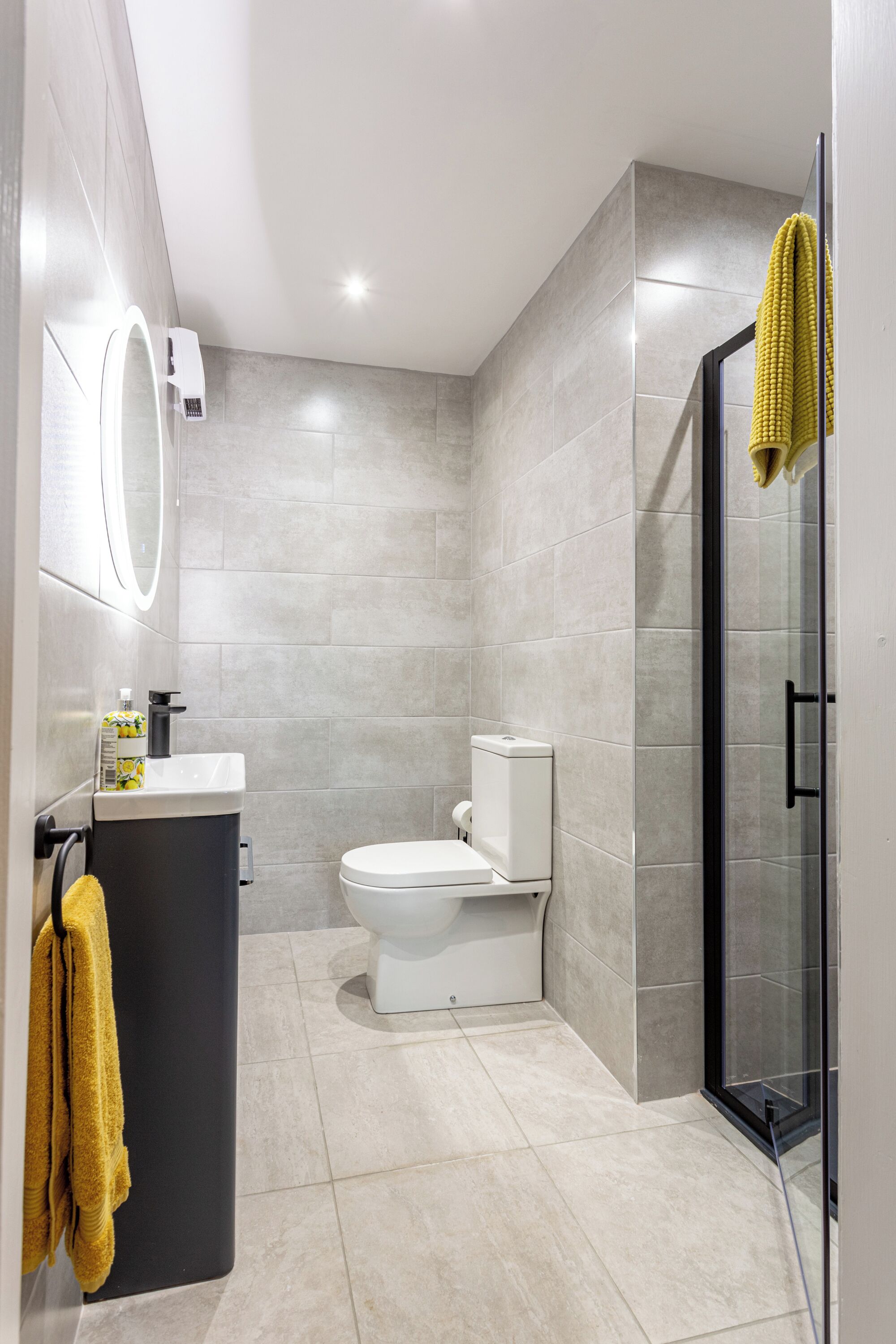 Une salle de bain moderne équipée de toilettes, d’un lavabo et d’une zone douche.