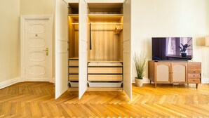A walk-in closet with sliding doors, wooden flooring, and a TV on a wooden cabinet. - Premium Suite in West Berlin, Sleeps 4, Family & Group Friendly, 70m to Metro (Berlin)