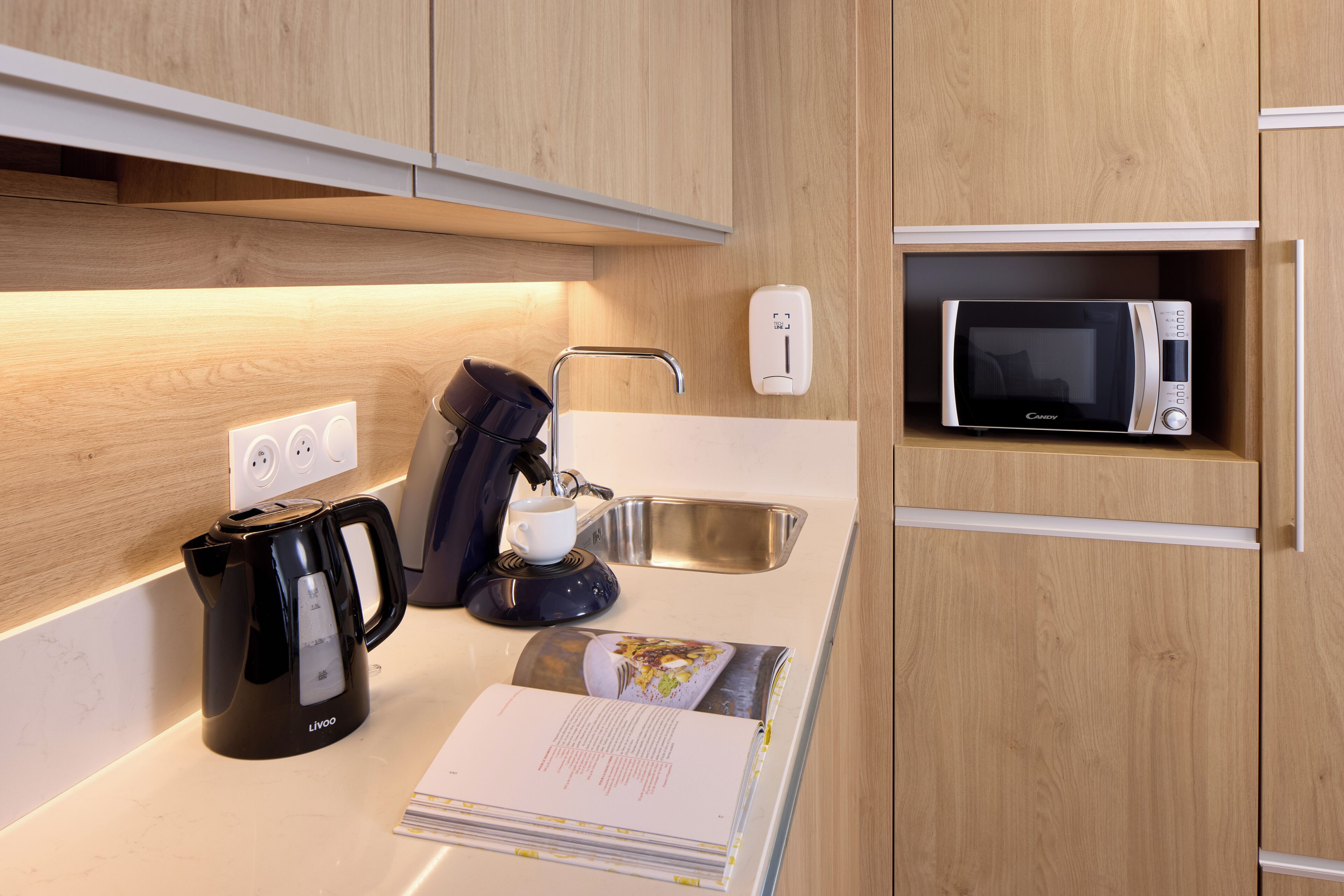 A modern kitchen with a built-in microwave, a kettle, and a coffee maker.