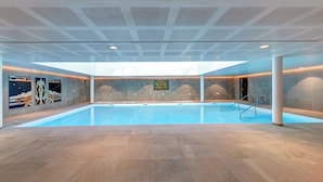 An indoor swimming pool with a tiled floor, a ceiling with a geometric pattern, and wall art. - Zenitude Hôtel-Résidences Val d'Europe (Chessy)