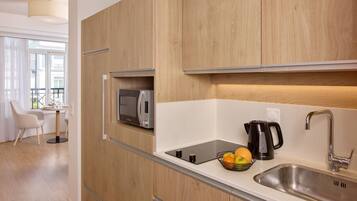 A modern kitchen with wooden cabinets, a built-in microwave, a kettle, and a fruit bowl.
