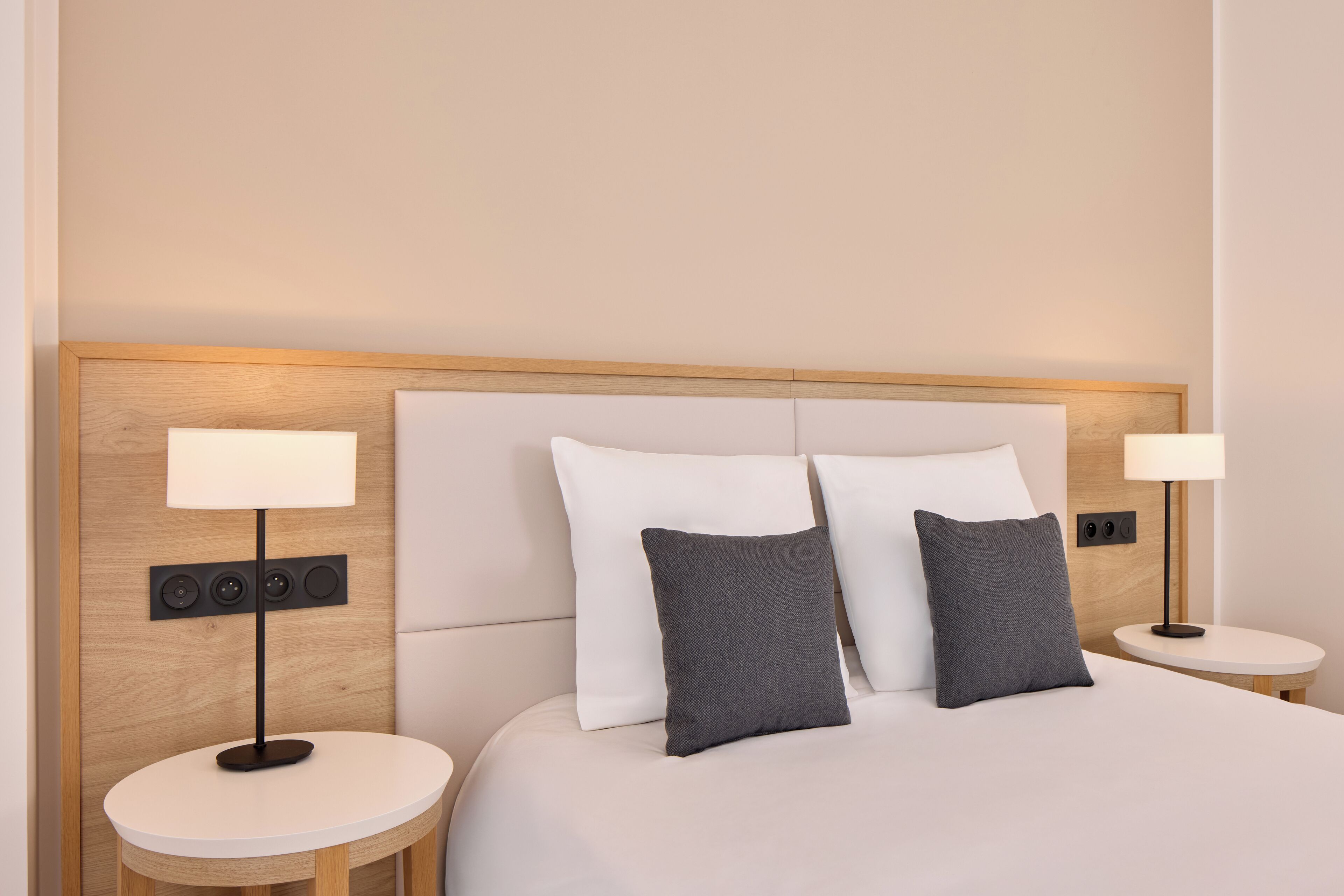 Una habitación de hotel con una cama, dos mesitas de noche y dos lámparas.