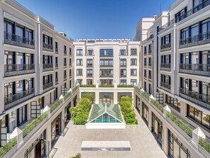 A modern multi-story building with a central courtyard featuring a glass-roofed swimming pool, surrounded by balconies with railings. - Quality Aparthotel Val d’Europe (Chessy)
