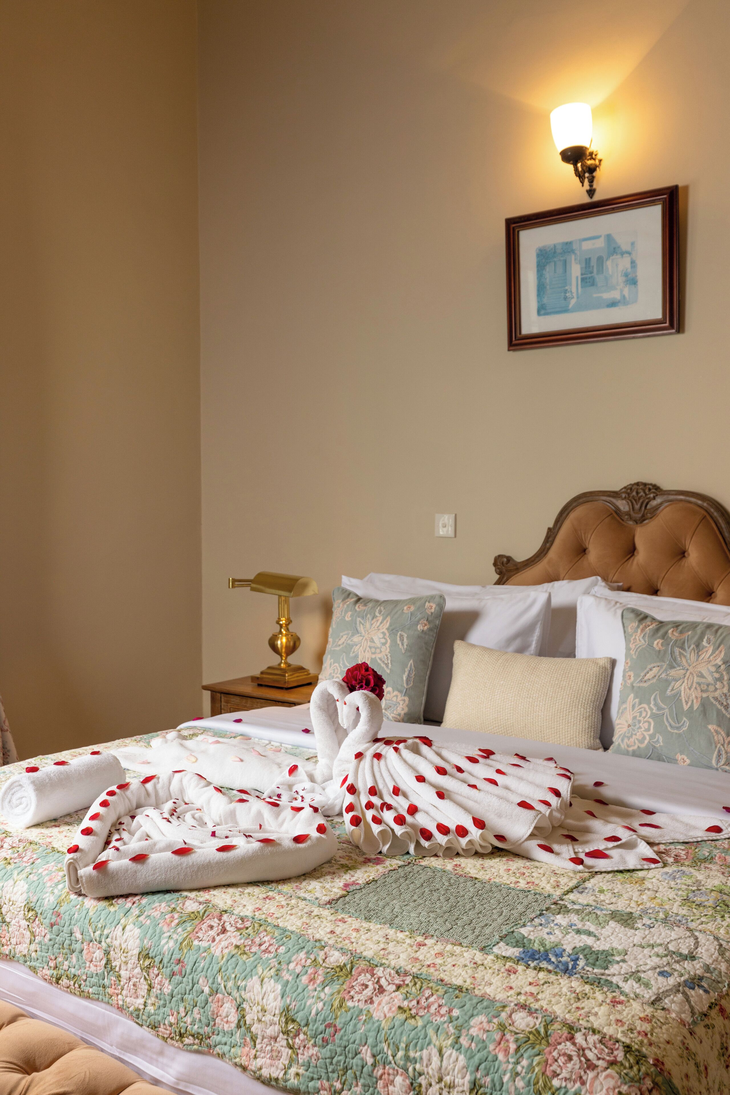 A neatly made bed with a floral quilt, a bedside lamp, and a framed picture on the wall.