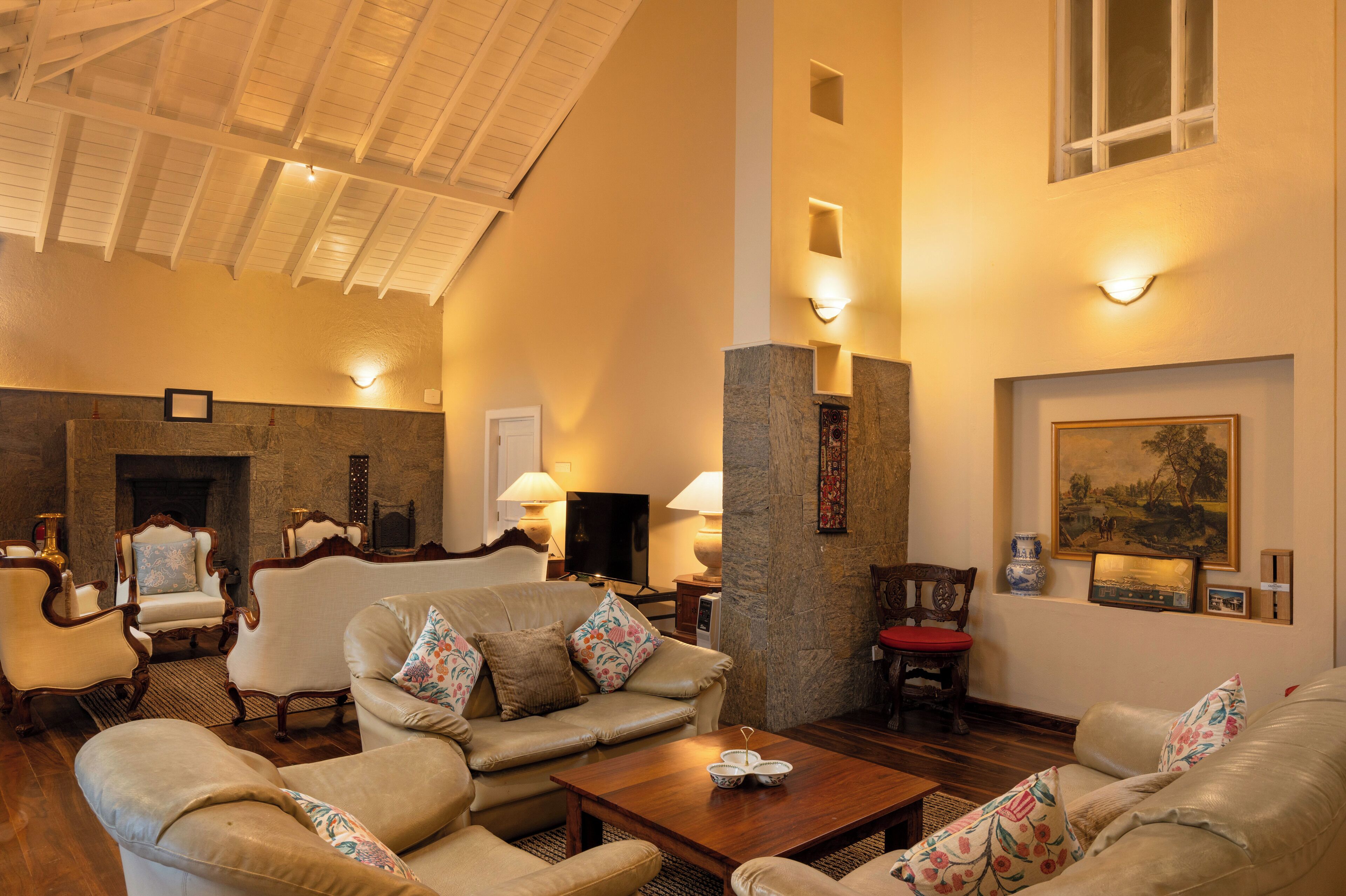 A spacious living room with a fireplace, comfortable seating, and a large painting on the wall.