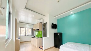 A compact room with a bed, a kitchenette, and a teal accent wall. - Tân Long Hotel (Ho Chi Minh City)