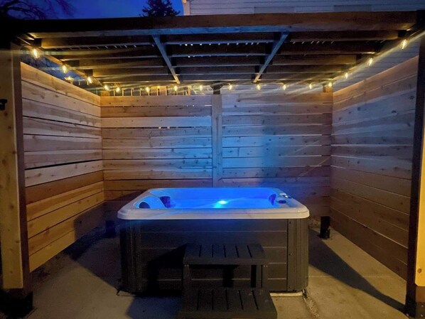 A hot tub in a wooden cabin with string lights.