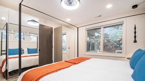 Une chambre avec un grand lit, une fenêtre et un miroir.